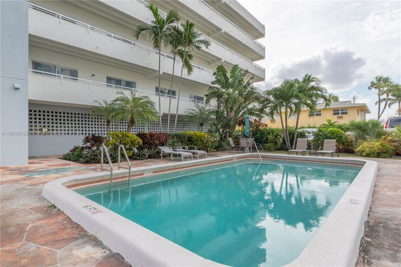 Outdoor swimming pool area with a multi-story building in the background.