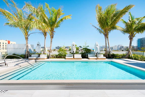 Outdoor swimming pool with loungers and palm trees.
