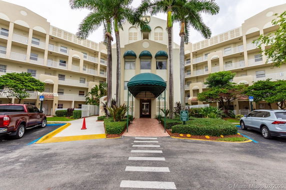 Front view of a multi-story residential building with balconies and an entrance canopy.