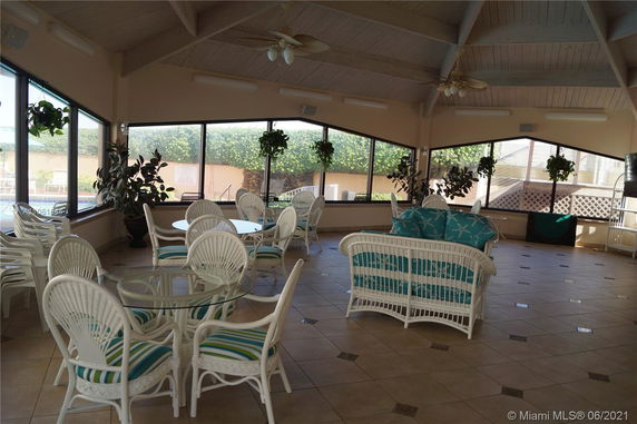 Indoor recreational area with wicker furniture and large windows.