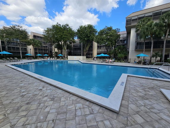 View of a residential complex with a central swimming pool and three-story buildings.