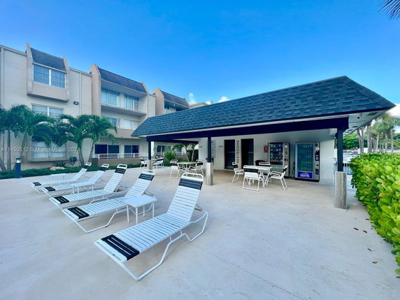 Outdoor area with lounge chairs and a covered seating area near a swimming pool.