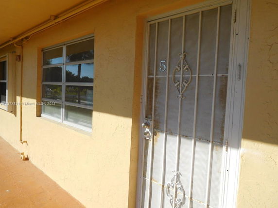 Front view of a house with a metal screen door and windows.