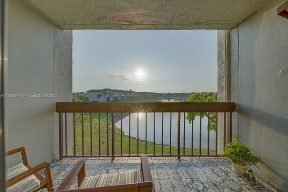 Balcony view overlooking a lake and distant buildings at sunset.