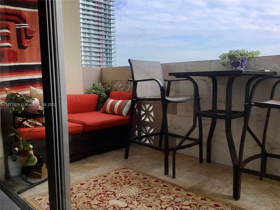 Apartment balcony with seating and a view of a nearby tall building.
