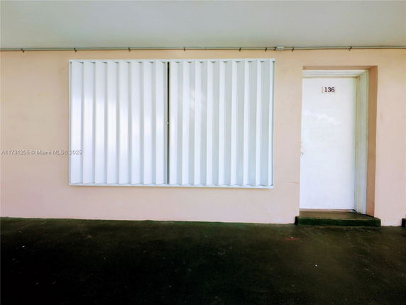 Front view of a building entrance with a door and a shuttered window.