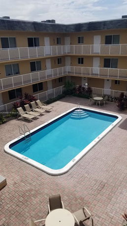 Outdoor swimming pool surrounded by a multi-story building with balconies.