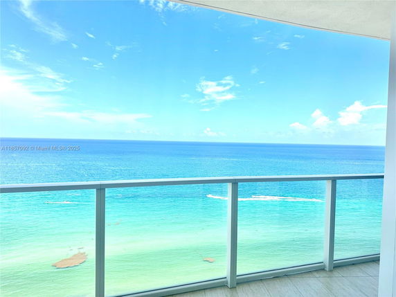 Panoramic view of the ocean from a balcony with glass railing.