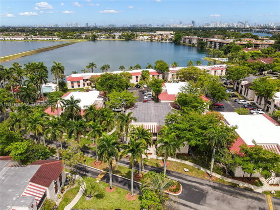 Aerial view of buildings near a lake with distant city skyline.