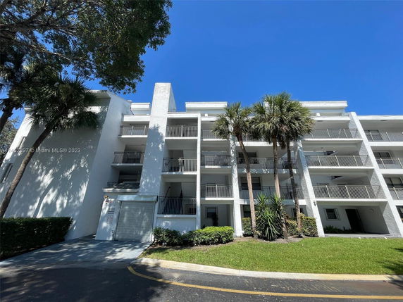 Front view of a multi-story apartment building with balconies and white exterior.