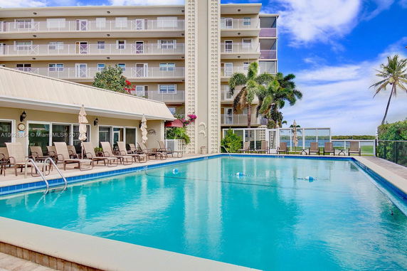 View of a multi-story building with balconies and a pool in the foreground.