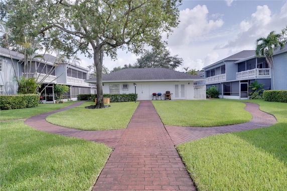 Exterior view of a small building surrounded by grass and larger residential buildings.