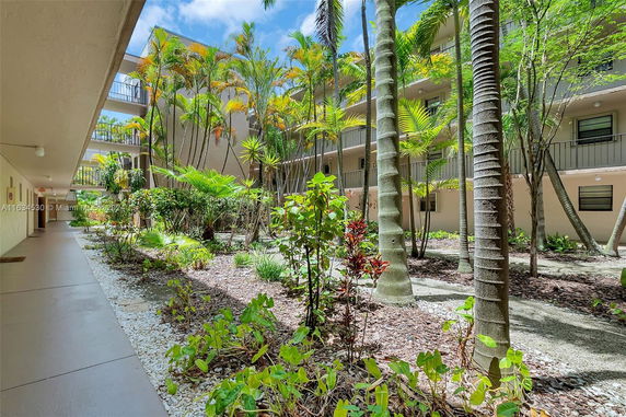 View of a multi-story building with tropical plants surrounding it.