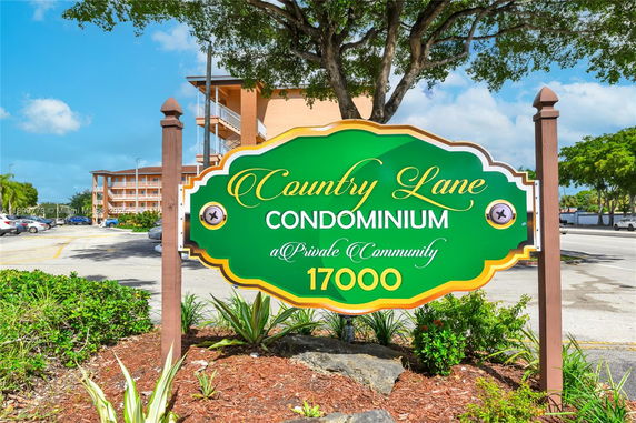 Front view of a multi-story condominium building behind a sign for 'Country Lane Condominium'.