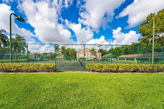 Outdoor tennis court with surrounding fence and green area.