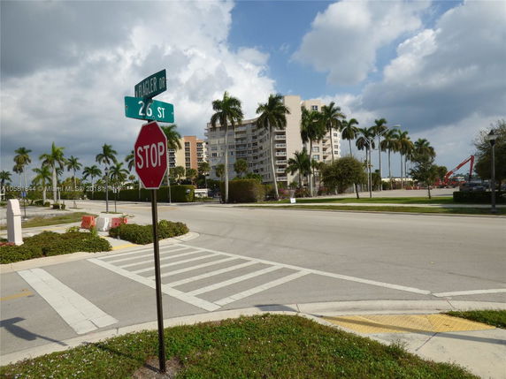 Urban street corner view with a multi-story residential building and palm trees.