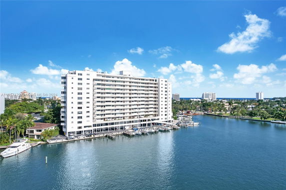 View of a large waterfront building with nearby water and surrounding landscape.