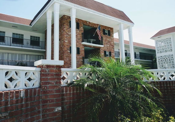 Front view of a multi-story building with brick and white pillars.