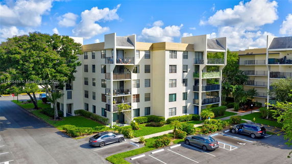 Front view of a multi-story apartment building with balconies and parking area.