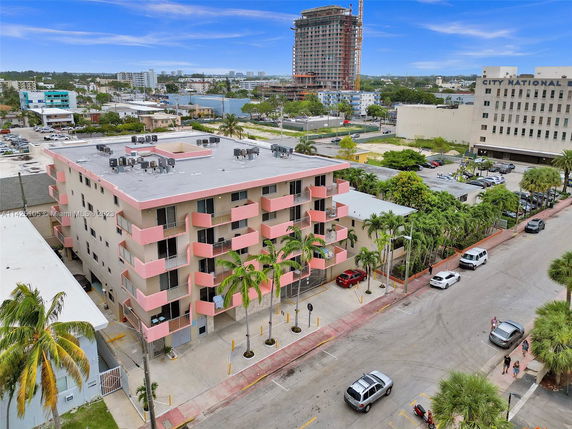 Rooftop view of a multi-story building with pink balconies and multiple air conditioning units on the roof.
