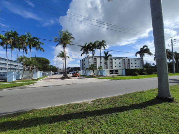 Front view of a multi-story residential building with palm trees nearby.