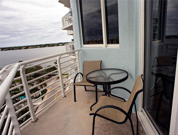 Balcony view from a high-rise building overlooking a body of water and distant landscape.