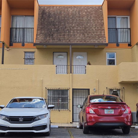 Front view of a two-story building with parking area in front.