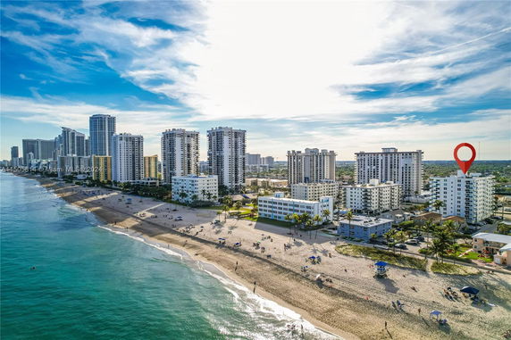 Panoramic view of beachfront high-rise buildings with a sandy beach in the foreground.