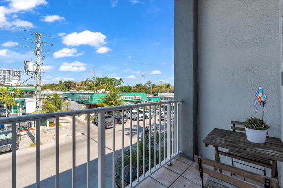 View from a balcony overlooking a parking area and nearby buildings.