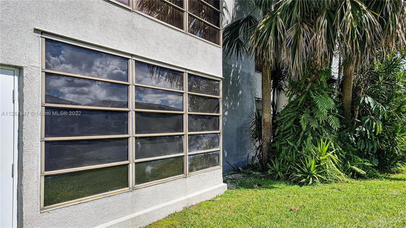 Exterior view of a building with large windows and adjacent vegetation.