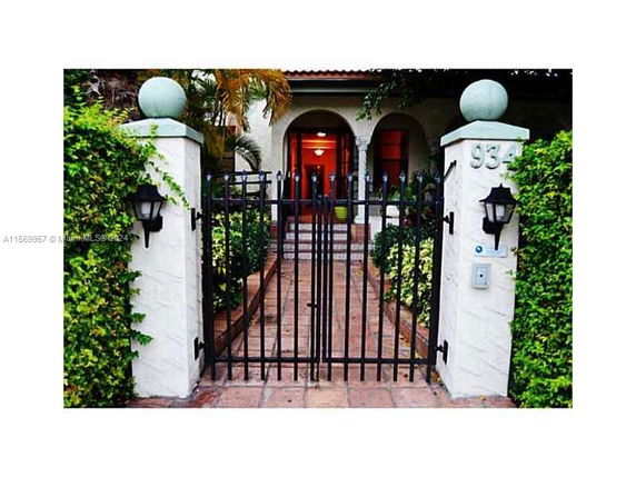 Front view of a house with a gated entrance and arched doorway.