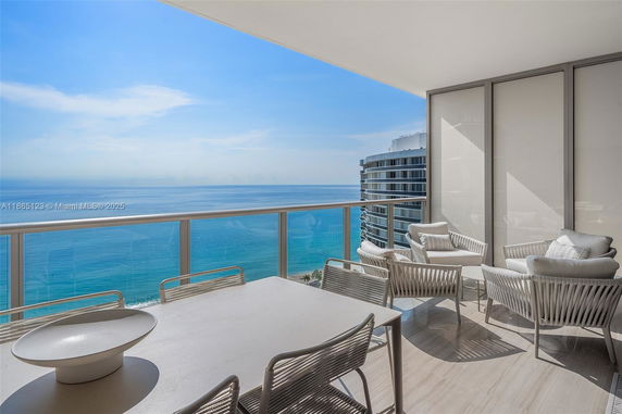 Balcony area with ocean view and outdoor furniture.