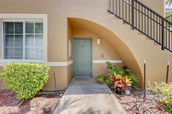 Front view of an apartment entrance with a green door and arched stairway.