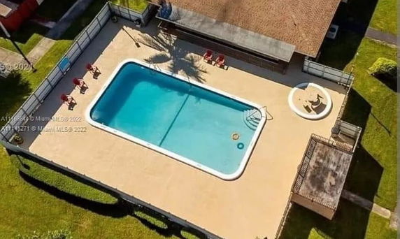 Aerial view of a rectangular swimming pool with sun loungers and seating area on a patio.