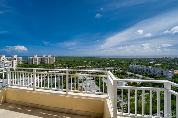 Panoramic view from a balcony overlooking a cityscape with buildings and greenery.