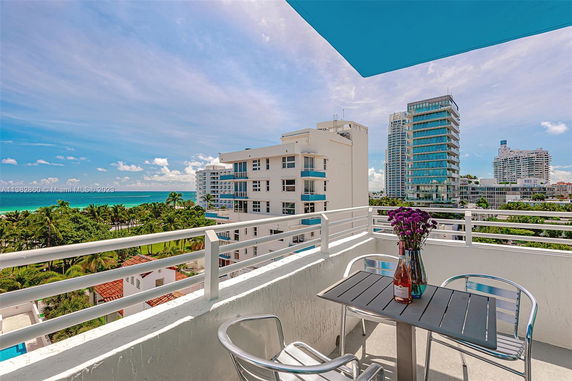 Balcony view with ocean and surrounding buildings.
