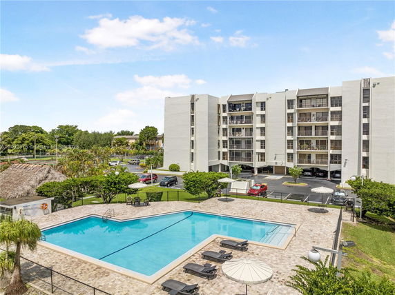 Outdoor swimming pool area with a multi-story residential building in the background.