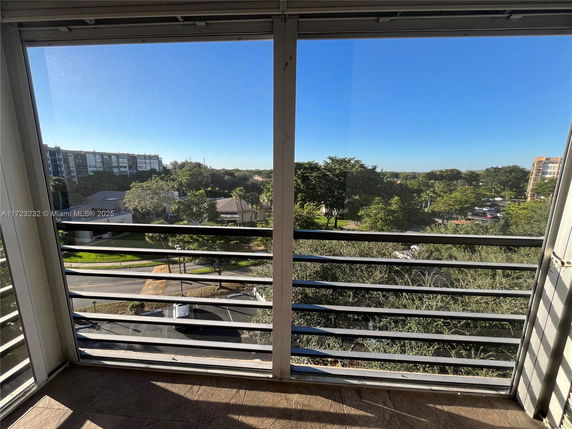 View from a balcony overlooking a parking area and surrounding buildings.