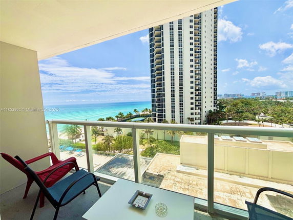 Balcony view overlooking the ocean with a high-rise building in the background.