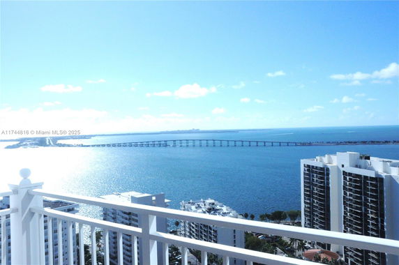 Panoramic view of a coastline with high-rise buildings and a distant bridge over water.