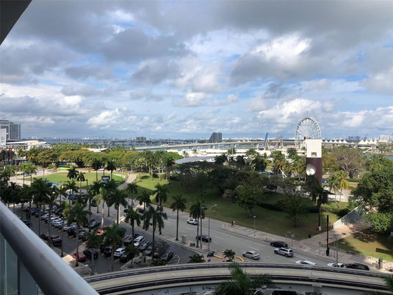 Panoramic view overlooking a park with trees and a ferris wheel in the background.