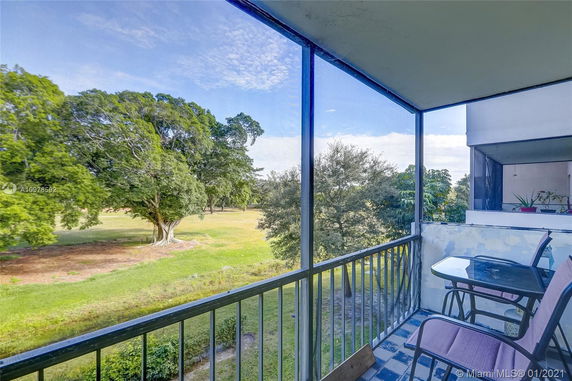 A balcony with a view of trees and open green space.