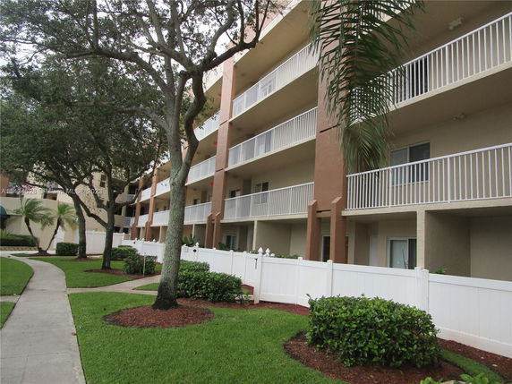 View of a multi-story residential building with balconies and white railings.