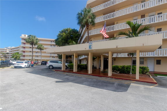 Front view of a multi-story building with balconies and a covered entrance.