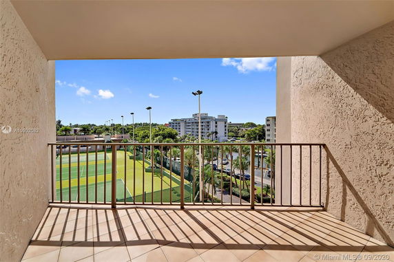Balcony view showing nearby buildings and a tennis court.