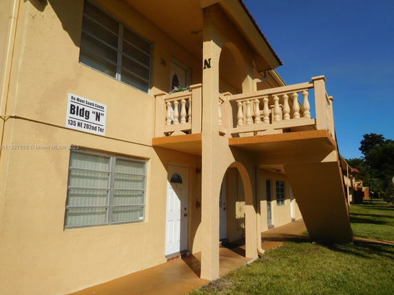 Front view of a two-story building with a balcony and several windows.