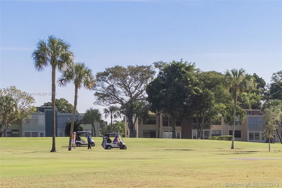 View of a golf course with buildings and trees in the background.