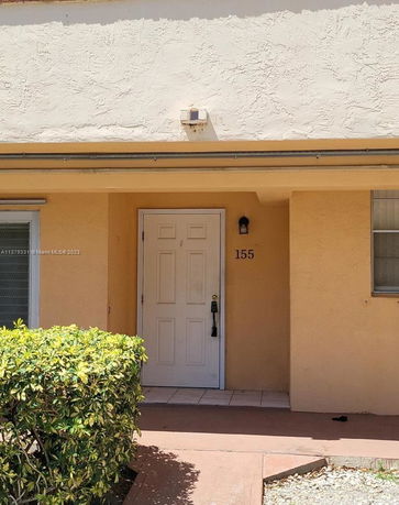 Entrance view of a house with a white door and beige exterior walls.