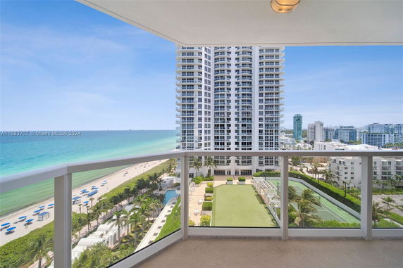 View from a high balcony showing a beachfront with a large building and ocean in the background.