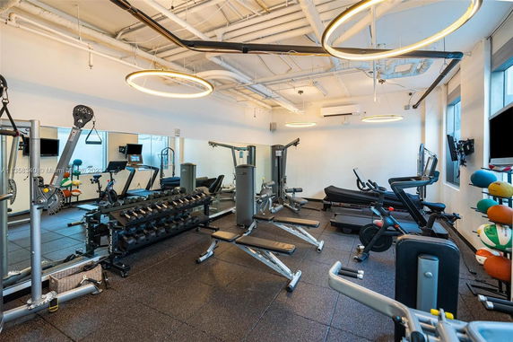 Indoor gym area with exercise equipment including treadmills, weights, and exercise bikes.